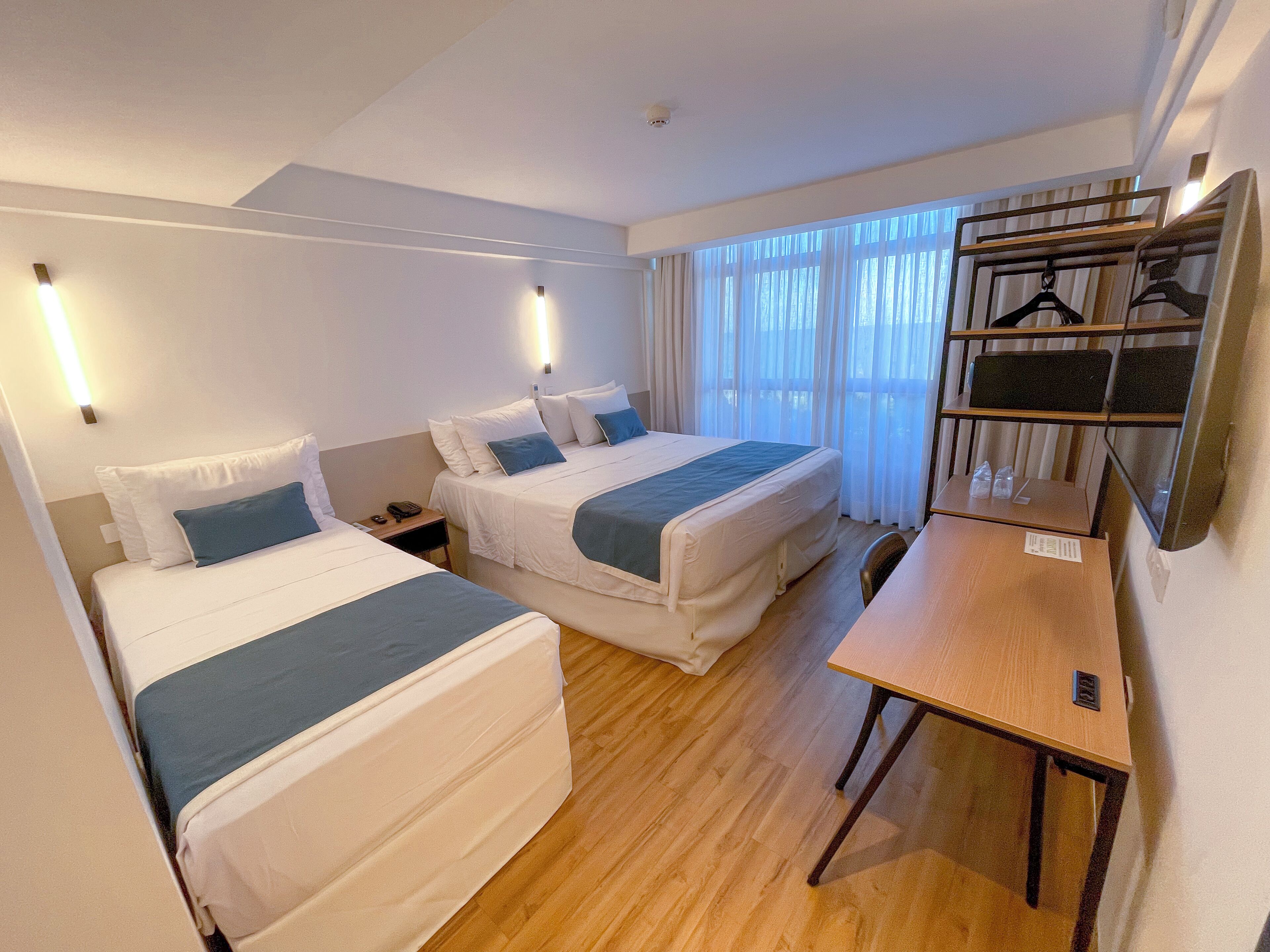 A hotel room with two beds, a desk, and a wardrobe.