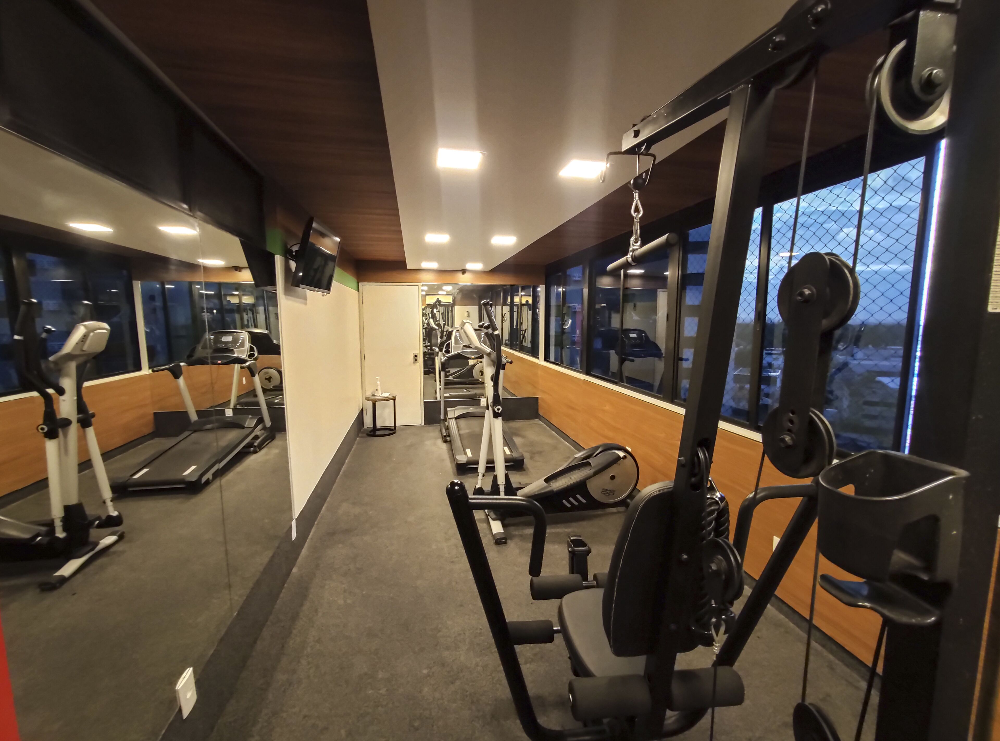 A gym with treadmills, weight machines, and a mirror wall.