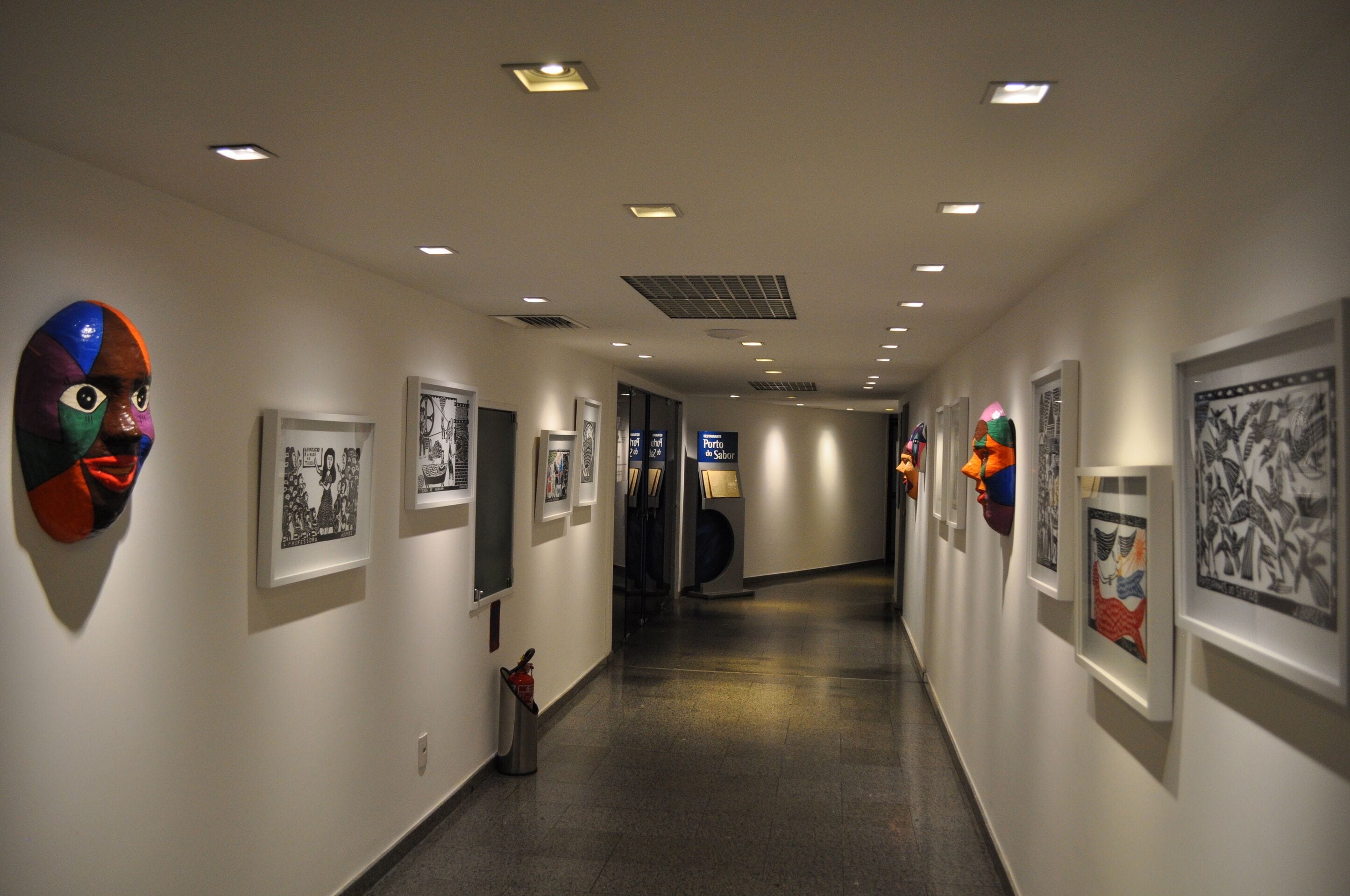 A hallway with art installations on the walls, a trash bin, and a sign for 'Porto'.