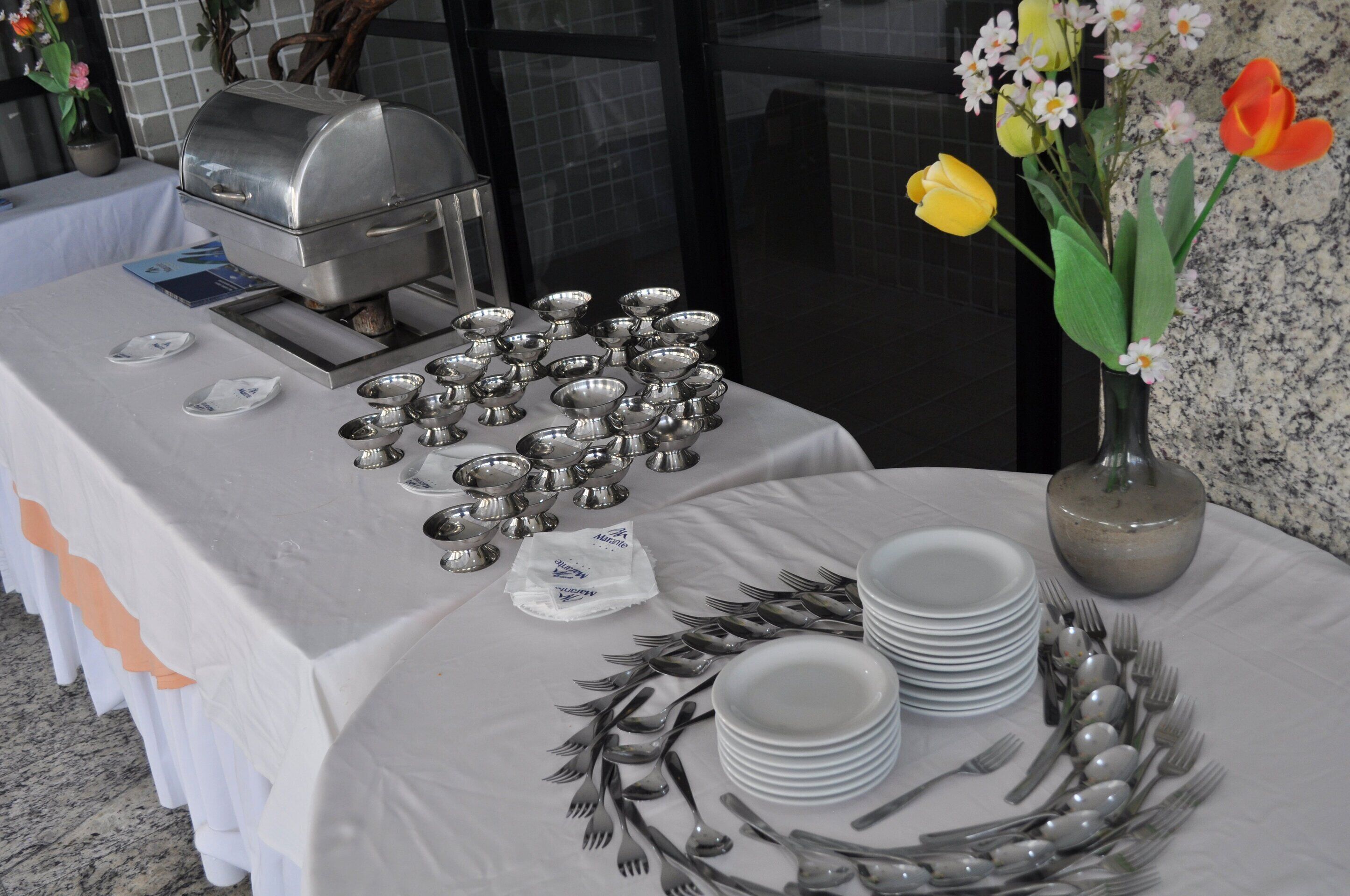 A buffet table with silverware, plates, and a food warmer.