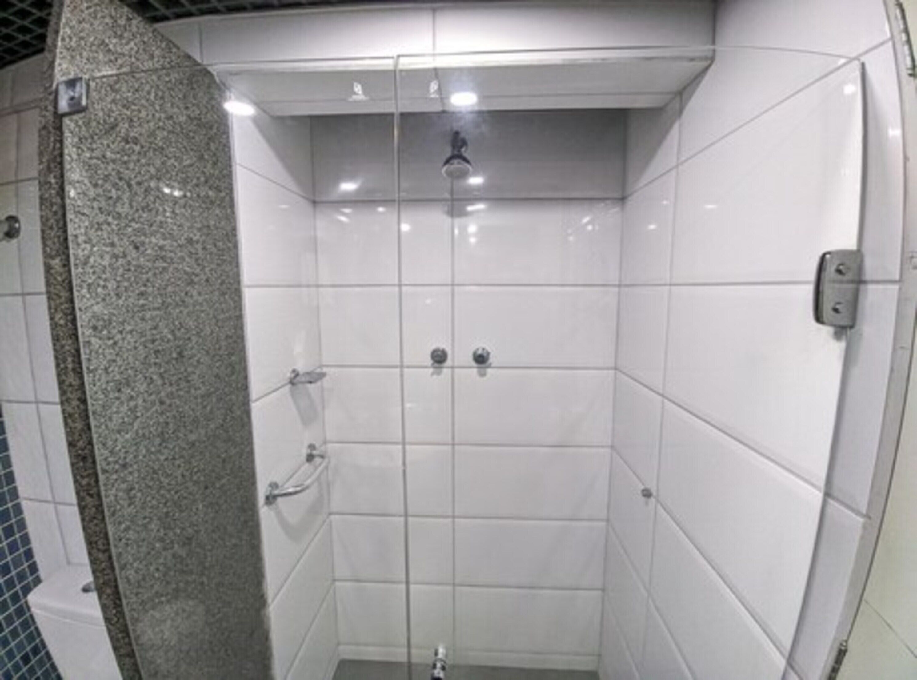 Un vestíbulo de ducha pequeño y cerrado, con azulejos blancos y una pared decorativa de granito.