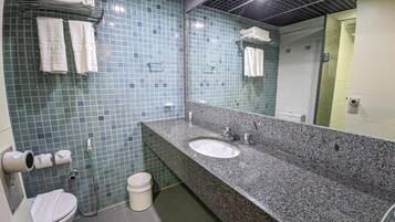 A bathroom with a granite countertop, two sinks, a toilet, and a shower.