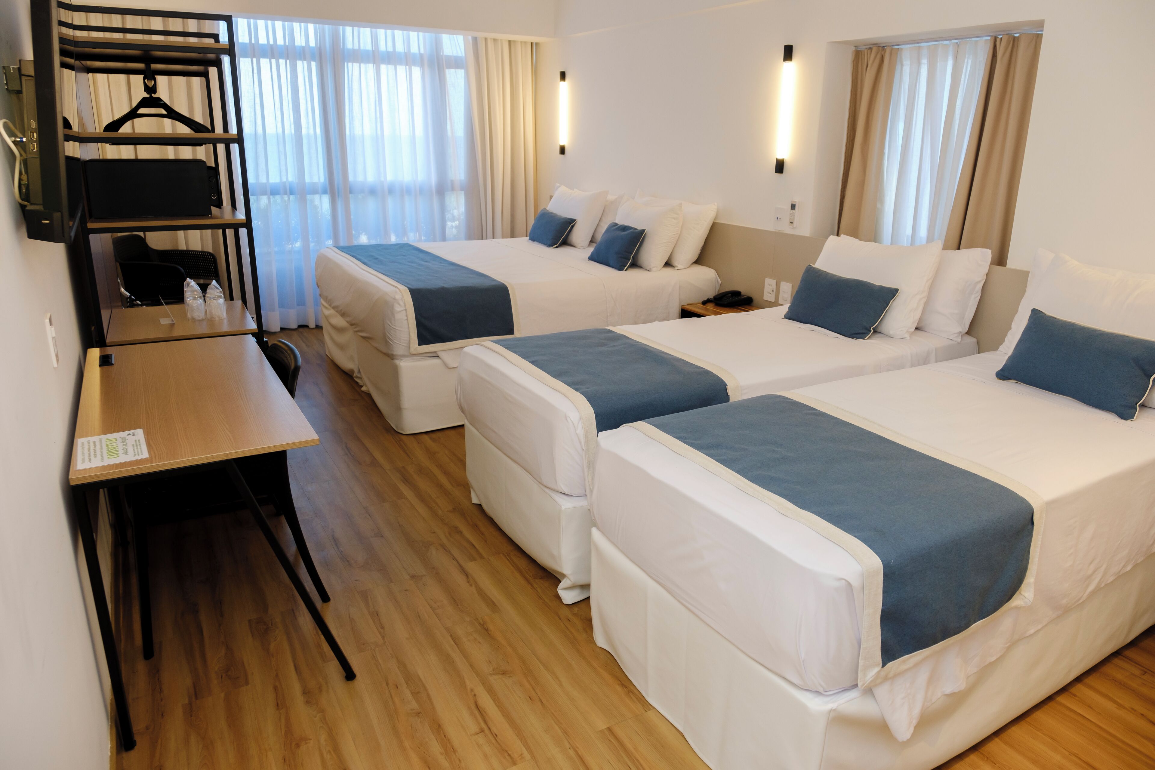 A hotel room with two single beds, a desk, a chair, and a wardrobe.
