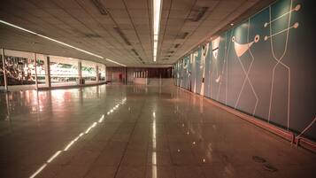 Un pasillo amplio y moderno con suelo pulido, ventanas grandes y arte abstracto en las paredes.
