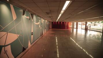 Un pasillo amplio con suelo de baldosas y una pared con diseños abstractos.