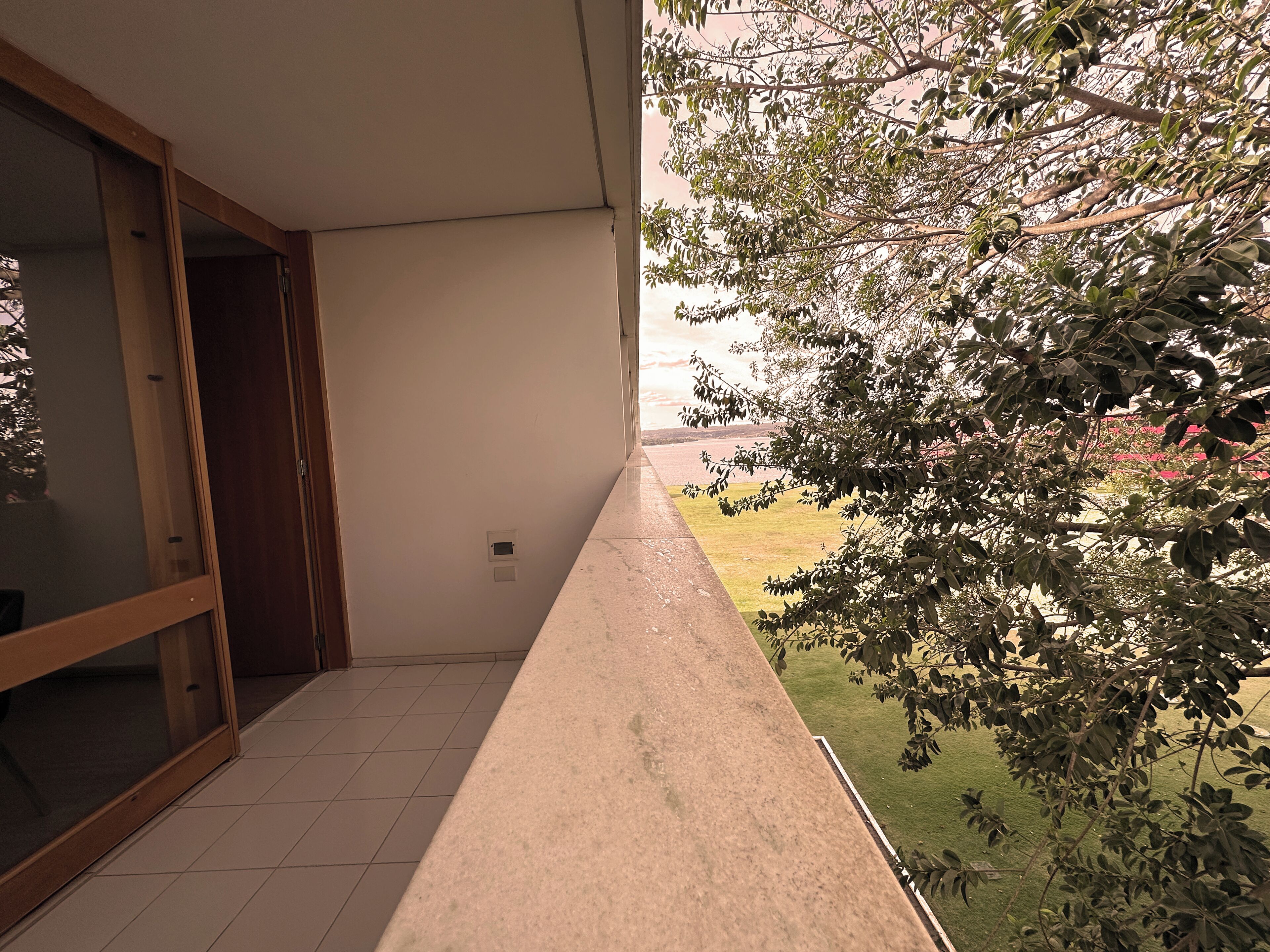 Un balcon donnant sur un espace verdoyant et des arbres.