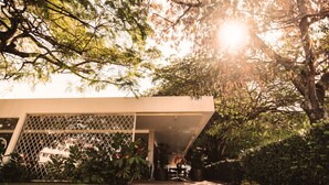 Un edificio moderno con vestíbulo cubierto, rodeado de vegetación exuberante y árboles.
