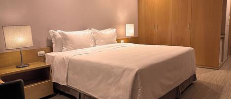 Cama bem arrumada com lençóis brancos em um quarto de hotel.
