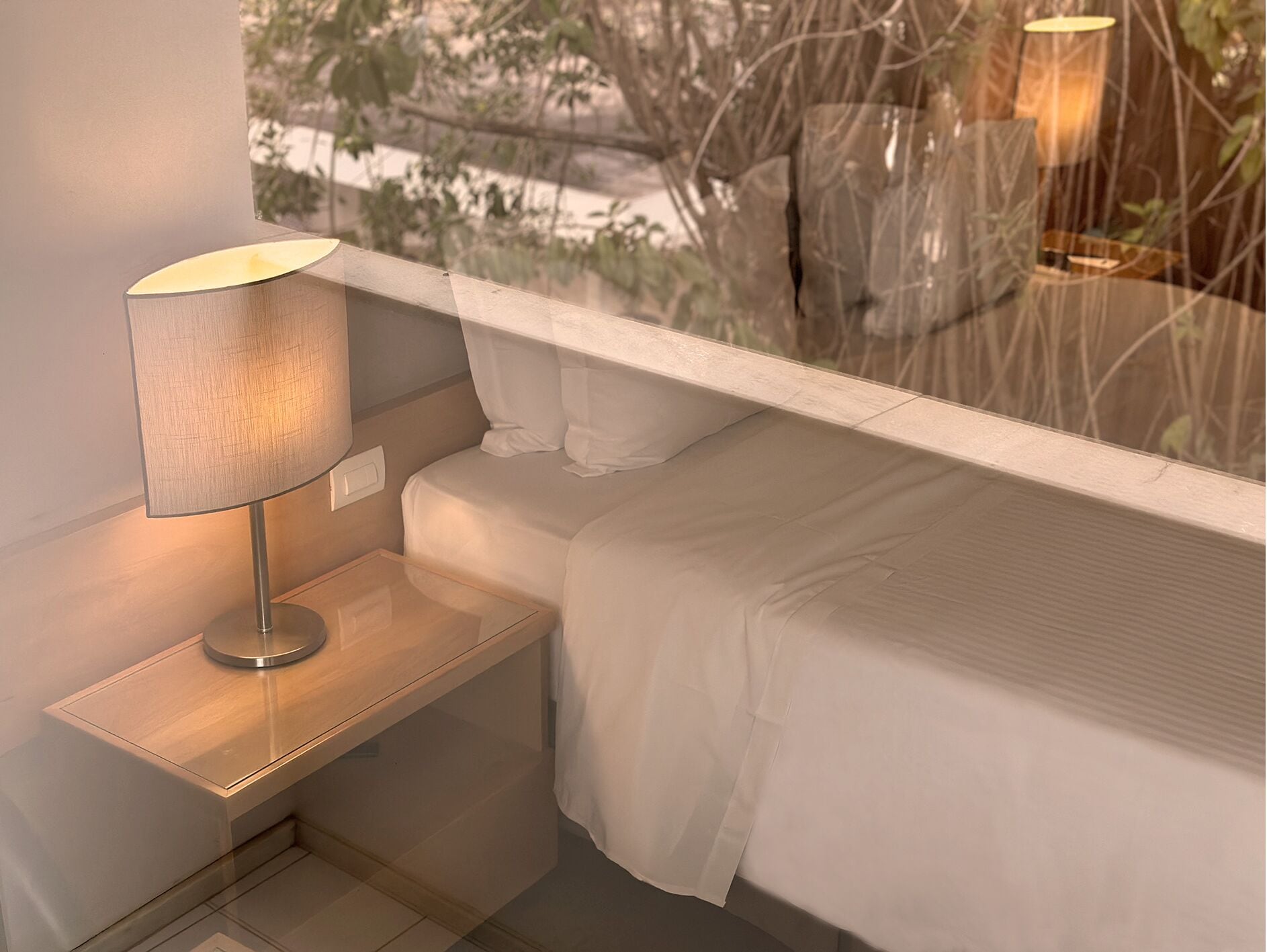 Un dormitorio moderno con una mesita de noche, una lámpara y una cama.