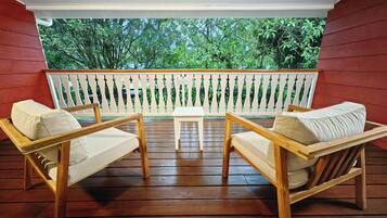 A wooden deck with two wooden chairs and a small table, surrounded by a white railing.