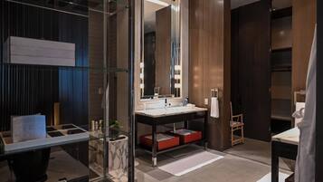 Un baño moderno con mampara de vidrio, tocador de madera, espejo grande y estante empotrado.