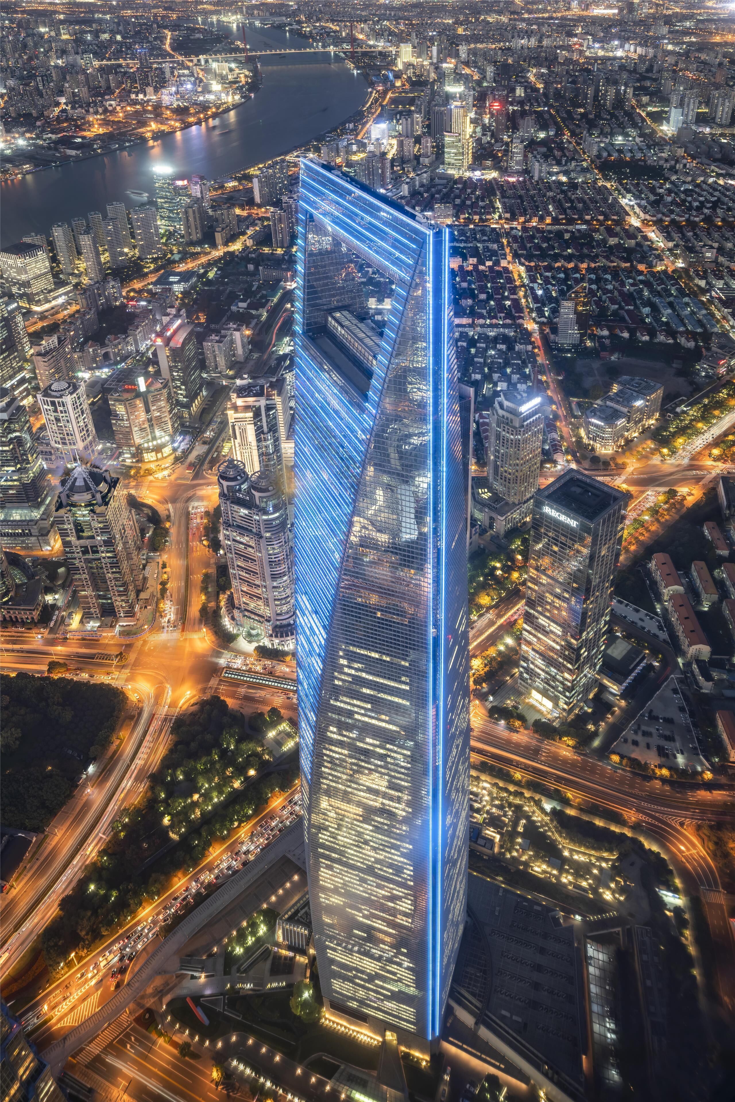 A high-rise building with a distinctive curved facade, surrounded by a dense urban environment with visible roads and other buildings.