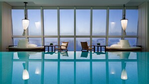 A swimming pool with chairs and tables, large windows, and hanging lamps. - Park Hyatt Shanghai (Shanghai)