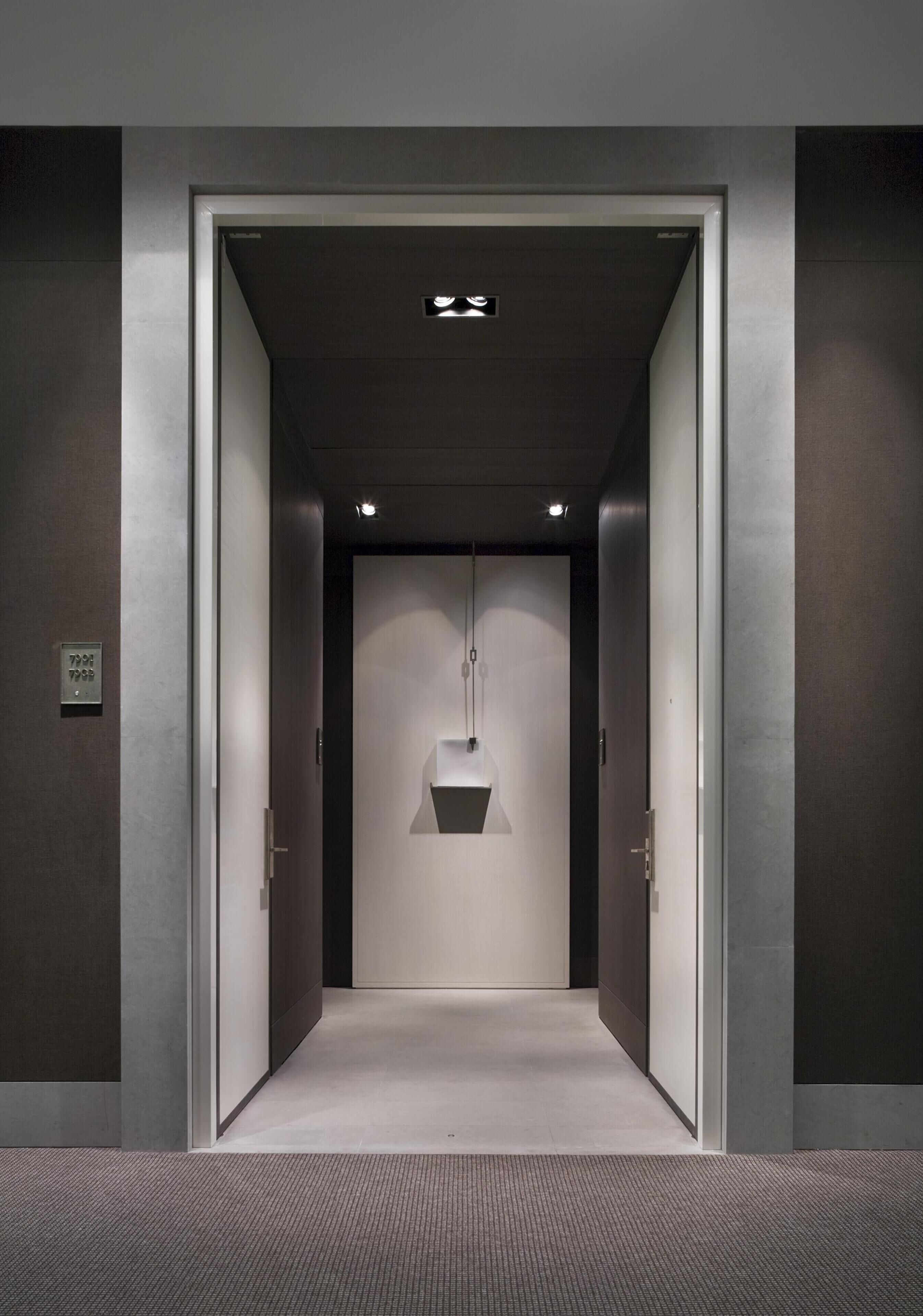 Un ascenseur au design moderne, doté d’un luminaire et d’un panneau de commande fixés au mur.