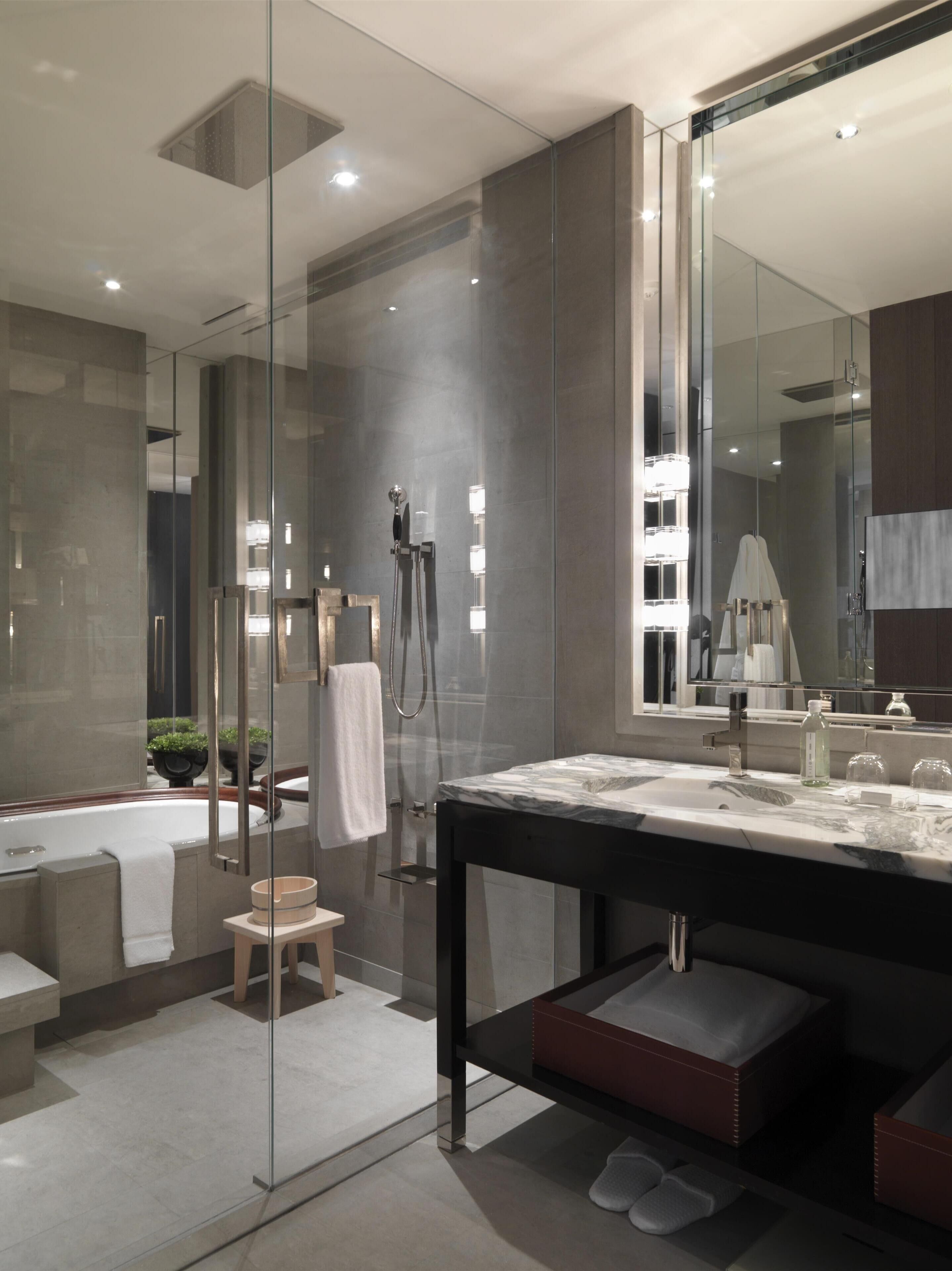 A modern bathroom with a glass-enclosed shower, a large mirror, and a marble sink.