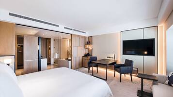 Een moderne hotelkamer met een groot bed, een bureau, een stoel, een bank, een televisie en een inloopkast.