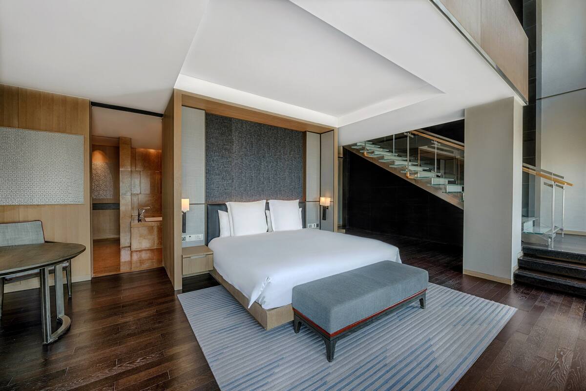 Une chambre d’hôtel moderne avec un grand lit, un bureau et un escalier.