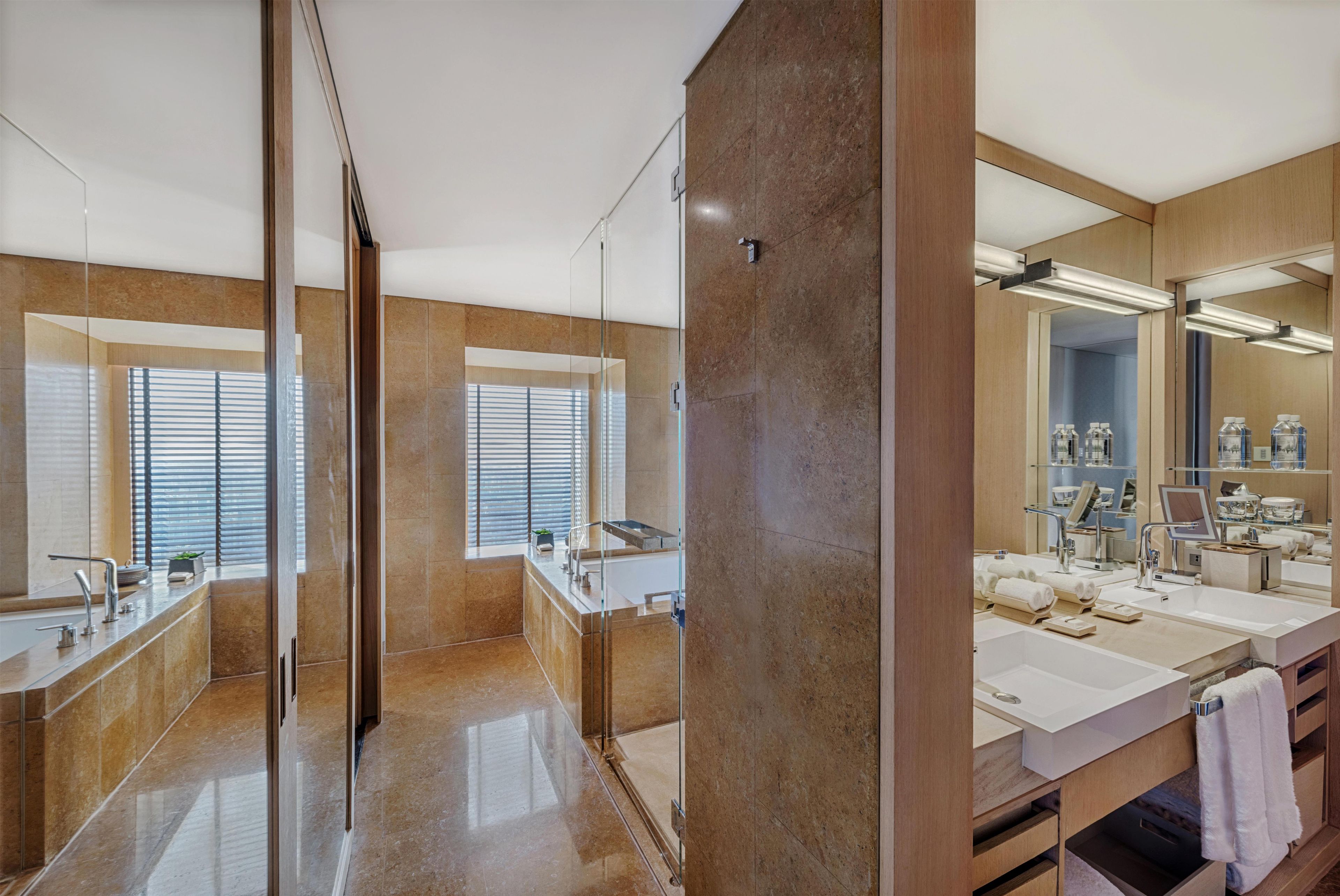 A modern bathroom with a large mirror, dual sinks, and a glass shower enclosure.