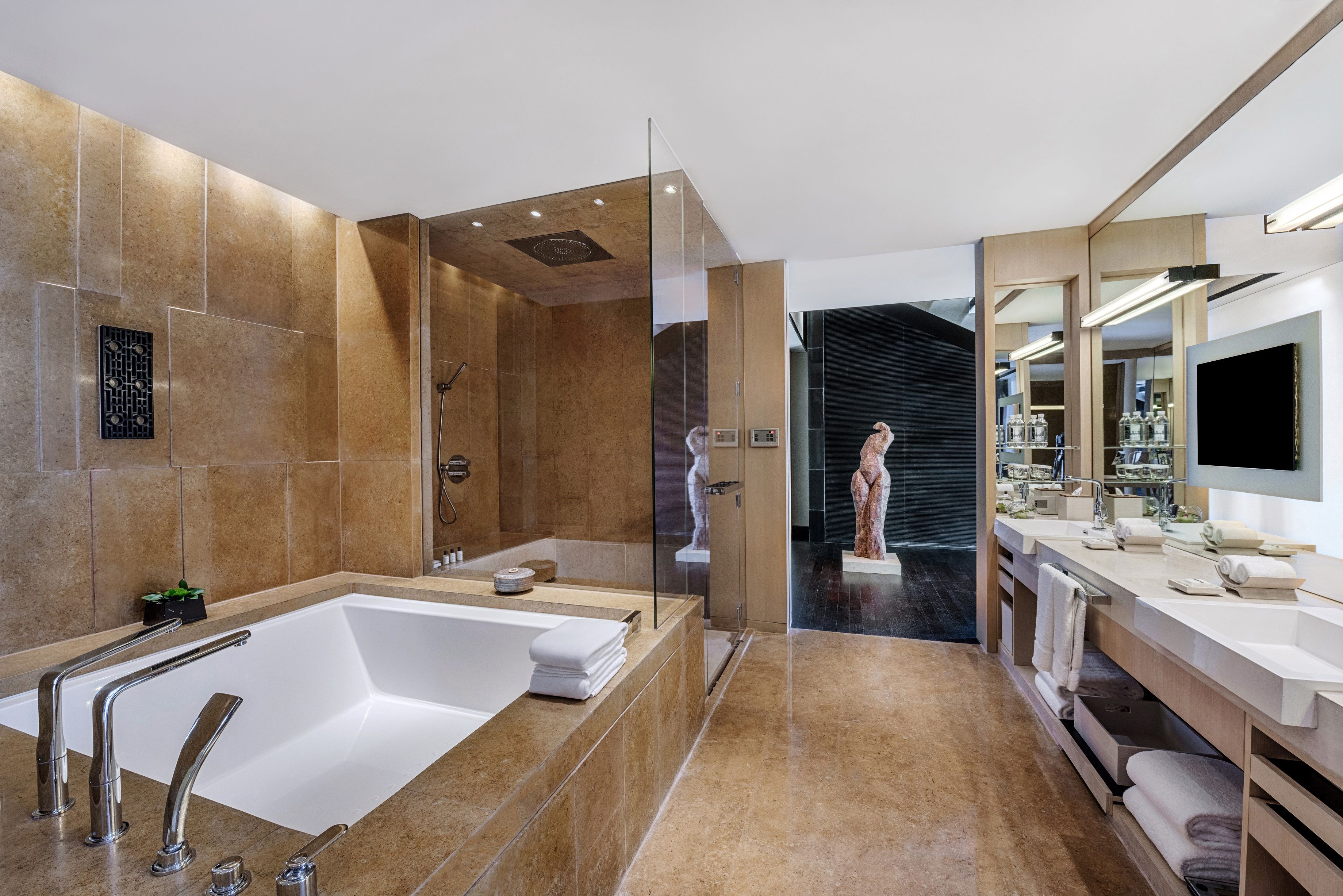 Un baño moderno con una bañera grande, cabina de ducha de vidrio y tocador con espejo y lavabo.