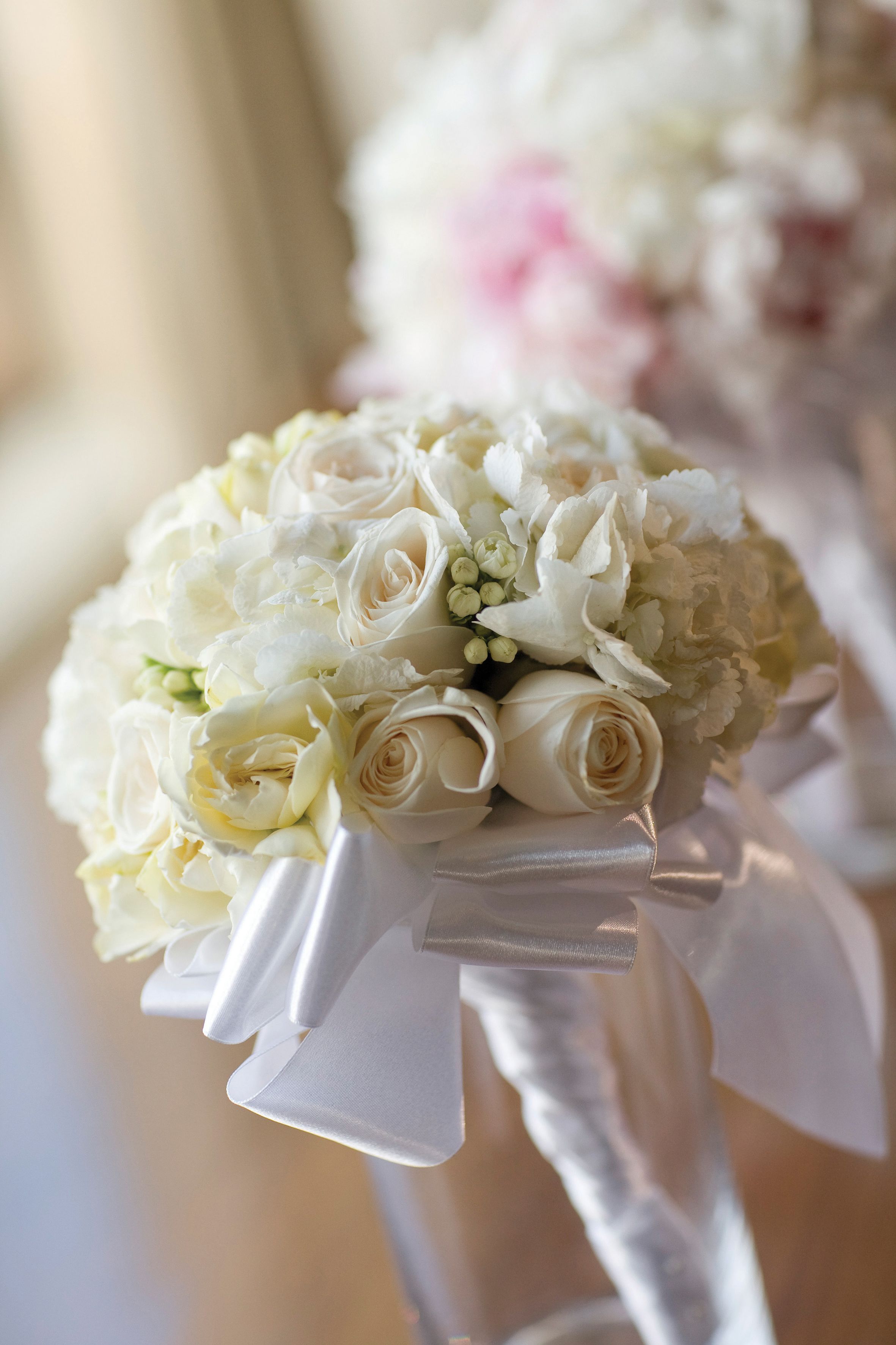 A bouquet of white flowers with a ribbon, likely for a wedding or formal event.