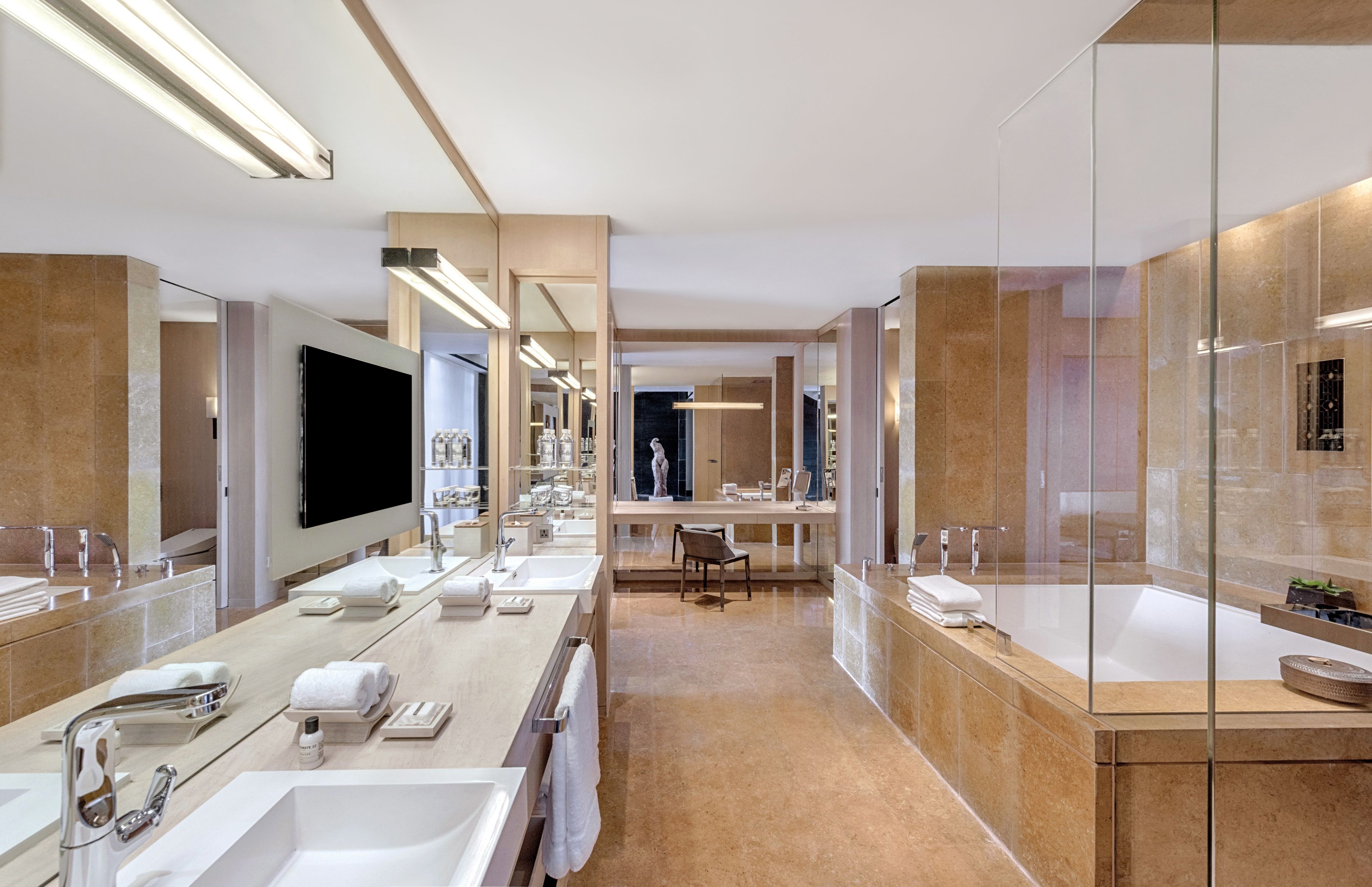 Een moderne badkamer met meerdere wasbakken, een grote spiegel en een bad.