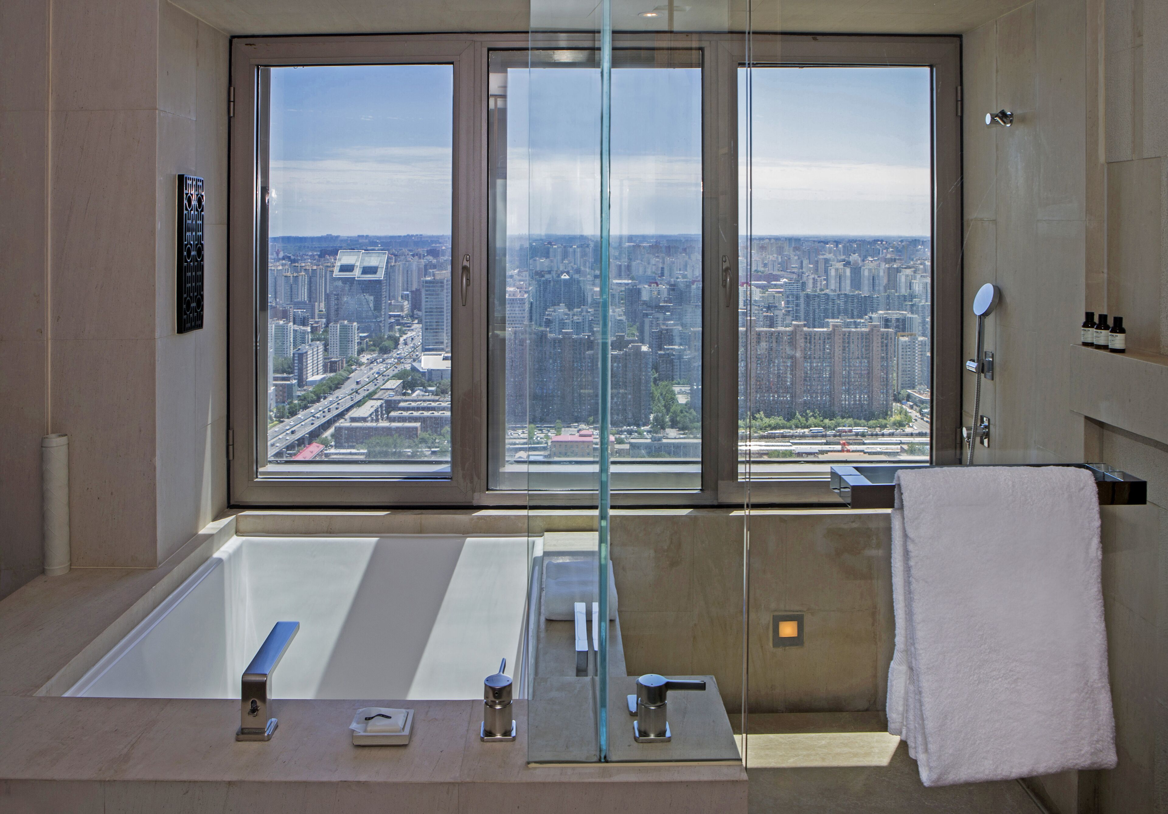 Een moderne badkamer met een groot raam, een badkuip, een douche en een handdoekrek.