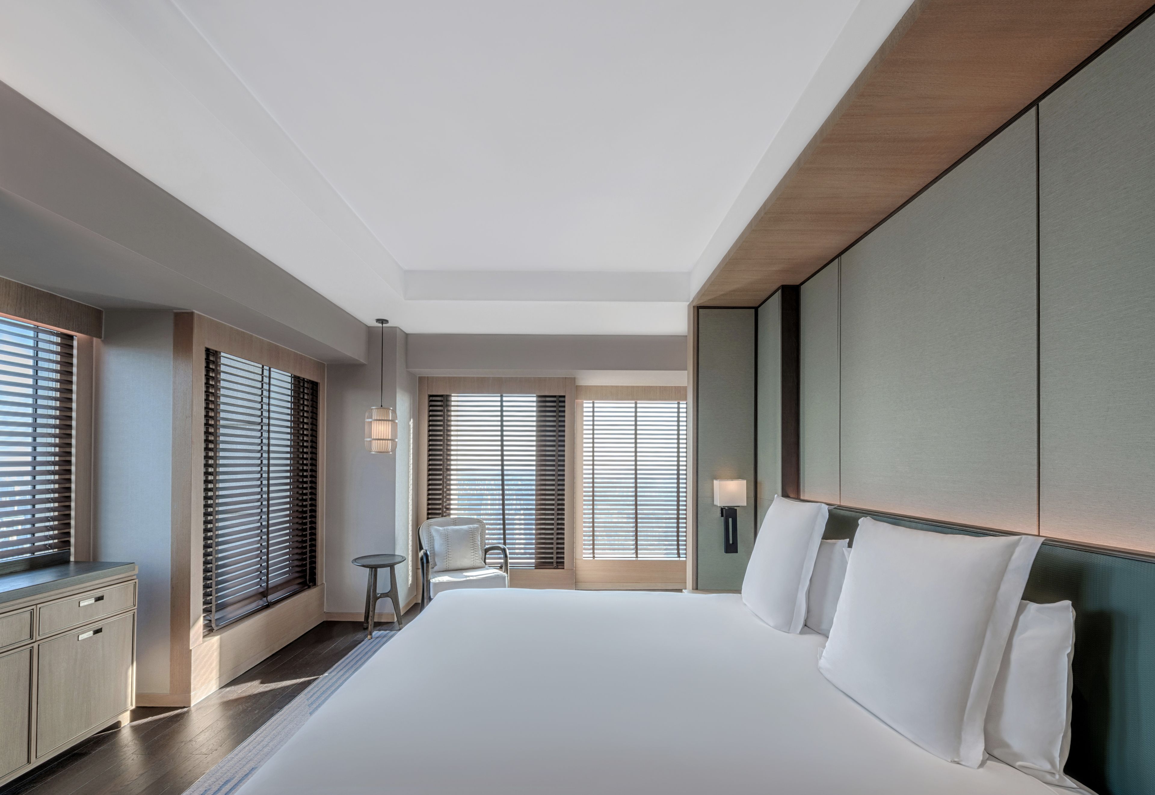 A modern hotel room with a large bed, a desk, and a chair.
