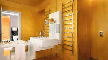Un baño moderno con un lavamanos, espejo y toallero blancos.
