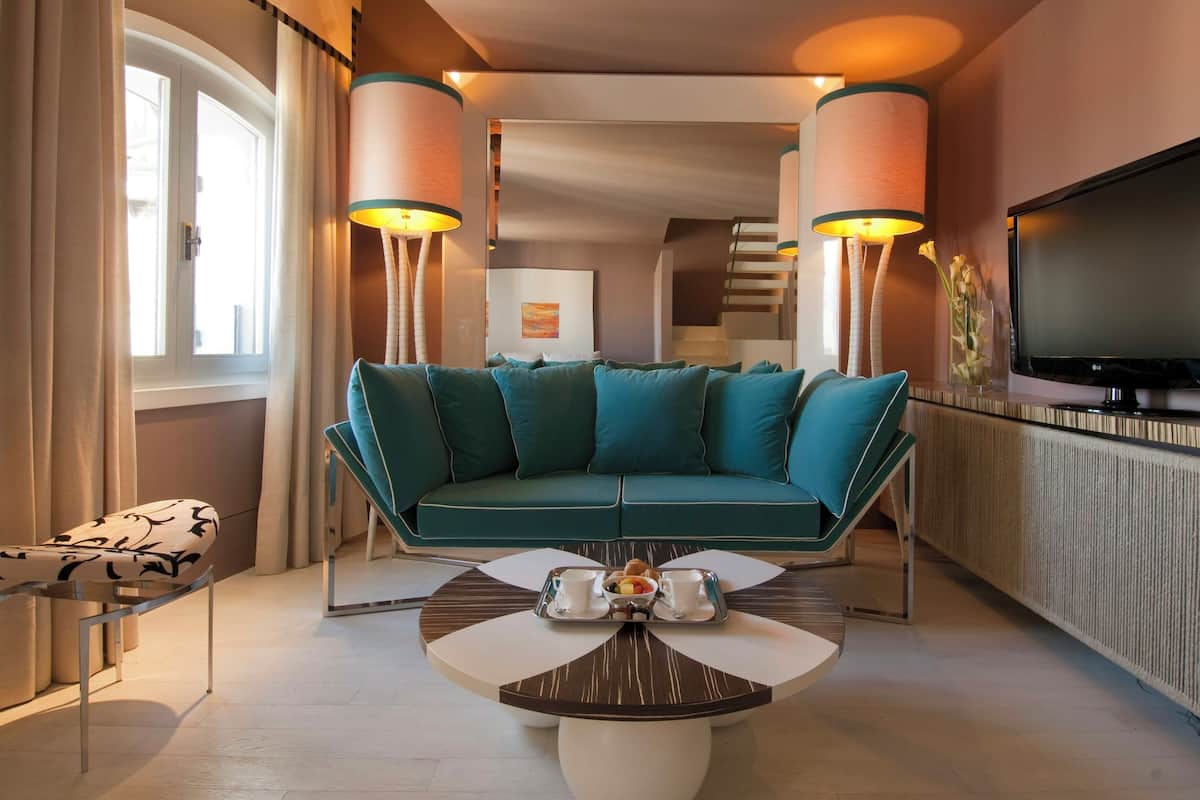 Una sala de estar moderna con un sofá color turquesa, una mesita de centro con una bandeja de alimentos para el desayuno y un televisor de pantalla plana montado en la pared.