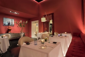 A dining area with tables set for service, a mirror, and a red upholstered bench. - Sina Centurion Palace (Venice)