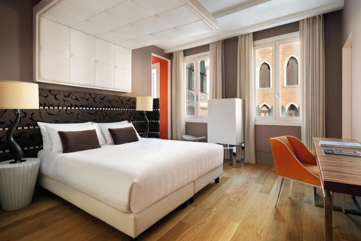 Una habitación de hotel con una cama grande, un escritorio y una silla.