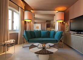 Una sala de estar moderna con un sofá color turquesa, una mesita de centro con una bandeja de alimentos para el desayuno y un televisor de pantalla plana montado en la pared.