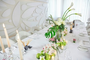 Una mesa de comedor formal decorada con velas, flores y manzanas verdes.