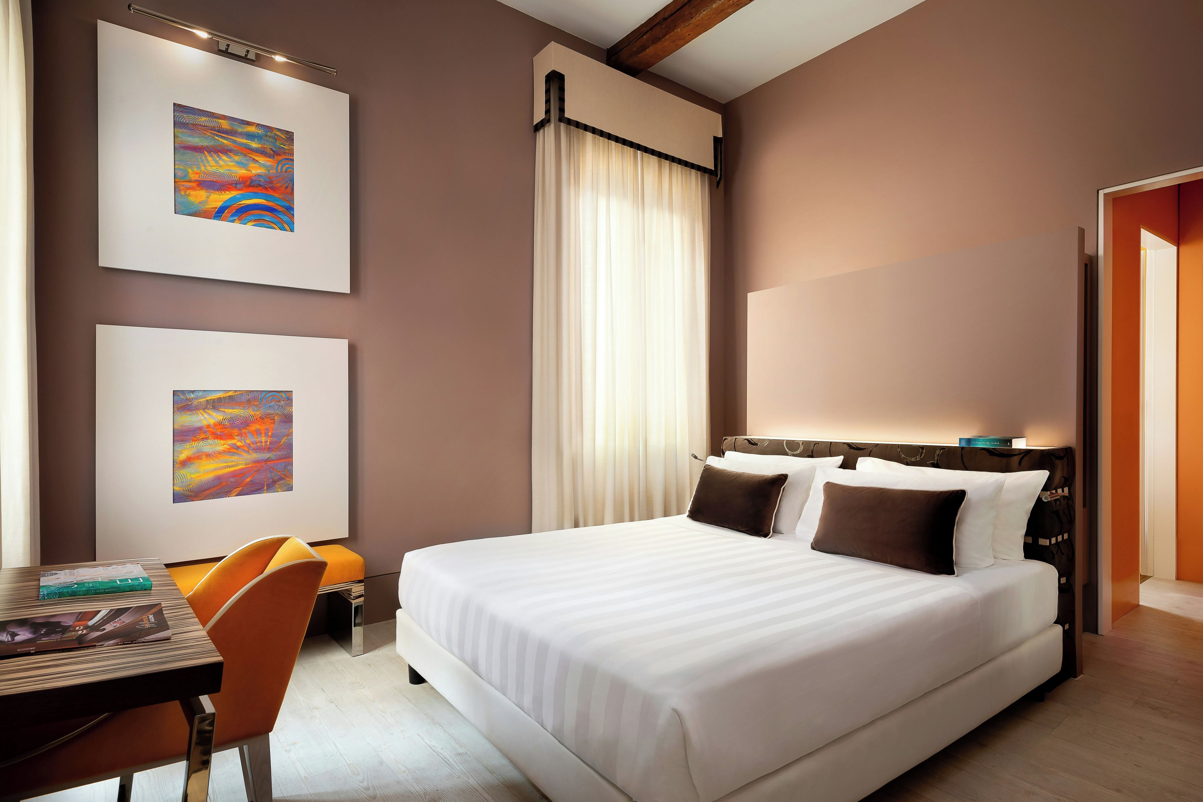 Una habitación de hotel con una cama grande, un escritorio con una silla y dos cuadros en la pared.