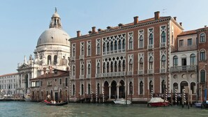Un edificio histórico con cúpula, ventanas de arco y un canal con góndolas.