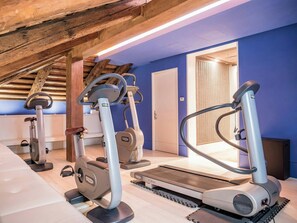 An indoor gym with exercise equipment, a wooden ceiling, and a blue wall. - Sina Centurion Palace (Venice)