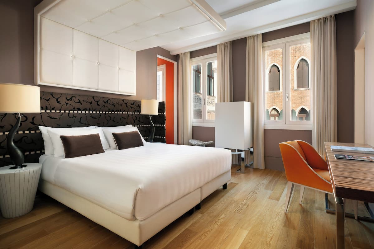 Una habitación de hotel con una cama grande, un escritorio y una silla.