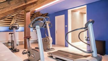 Un gimnasio interior con equipo de ejercicio, techo de madera y pared azul.