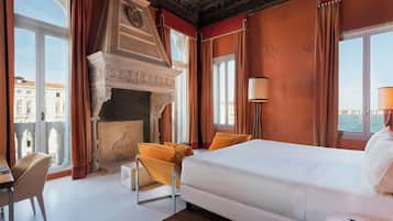 A hotel room with a large bed, a fireplace, a view of the city, and a desk with a chair.