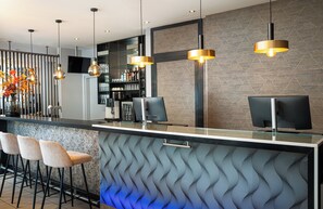 A modern bar area with a patterned wall, bar stools, and pendant lighting. -  Leonardo Hotel Salzburg City Center (Salzburg)