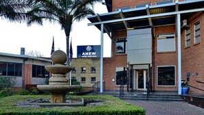 Ein Hotel Eingang mit einer Steinfunktion, einem Backsteingebäude und einem Schild für das Anew Hotel Highveld.