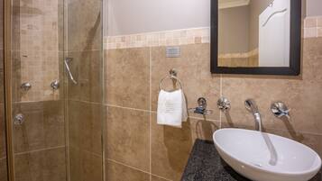 A bathroom with a glass-enclosed shower, a white sink, and a towel rack.