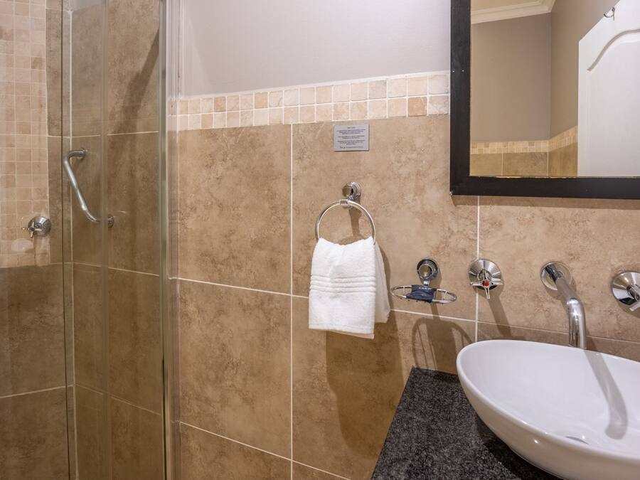 A bathroom with a glass-enclosed shower, a white sink, and a towel rack.