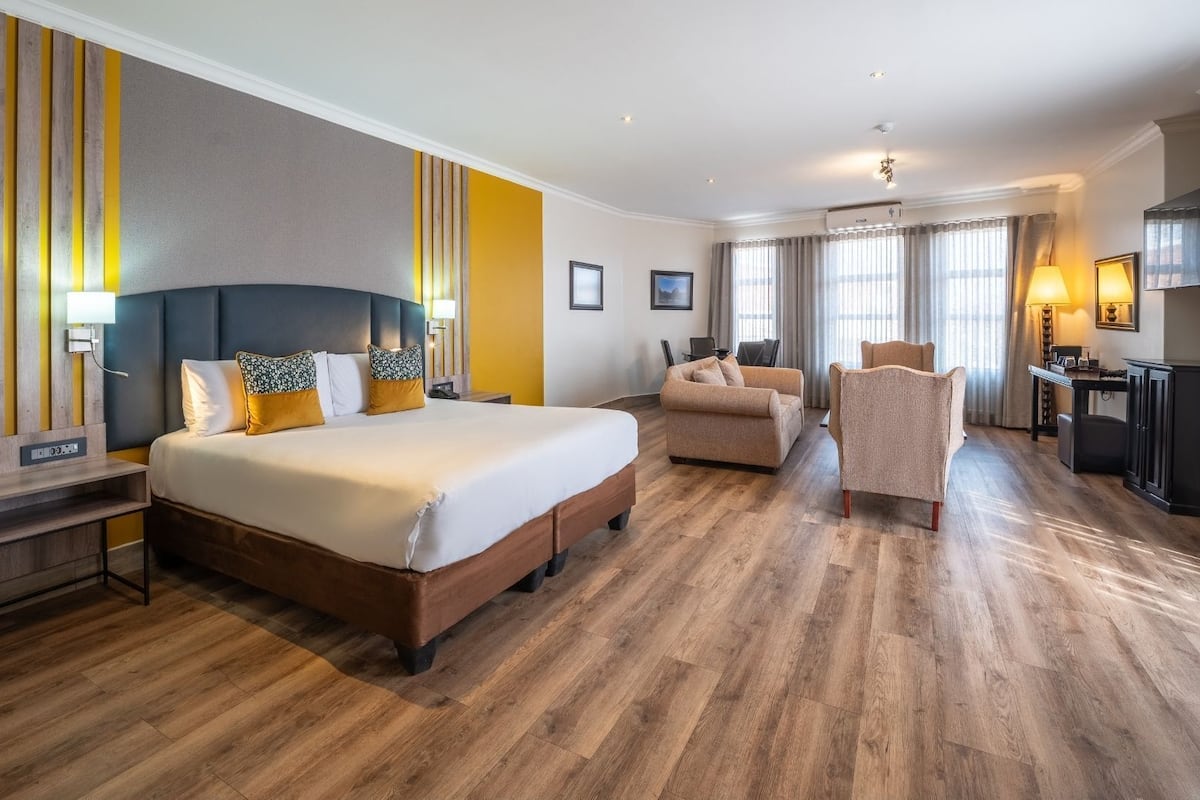 A hotel room with a large bed, a desk, a chair, and a TV.
