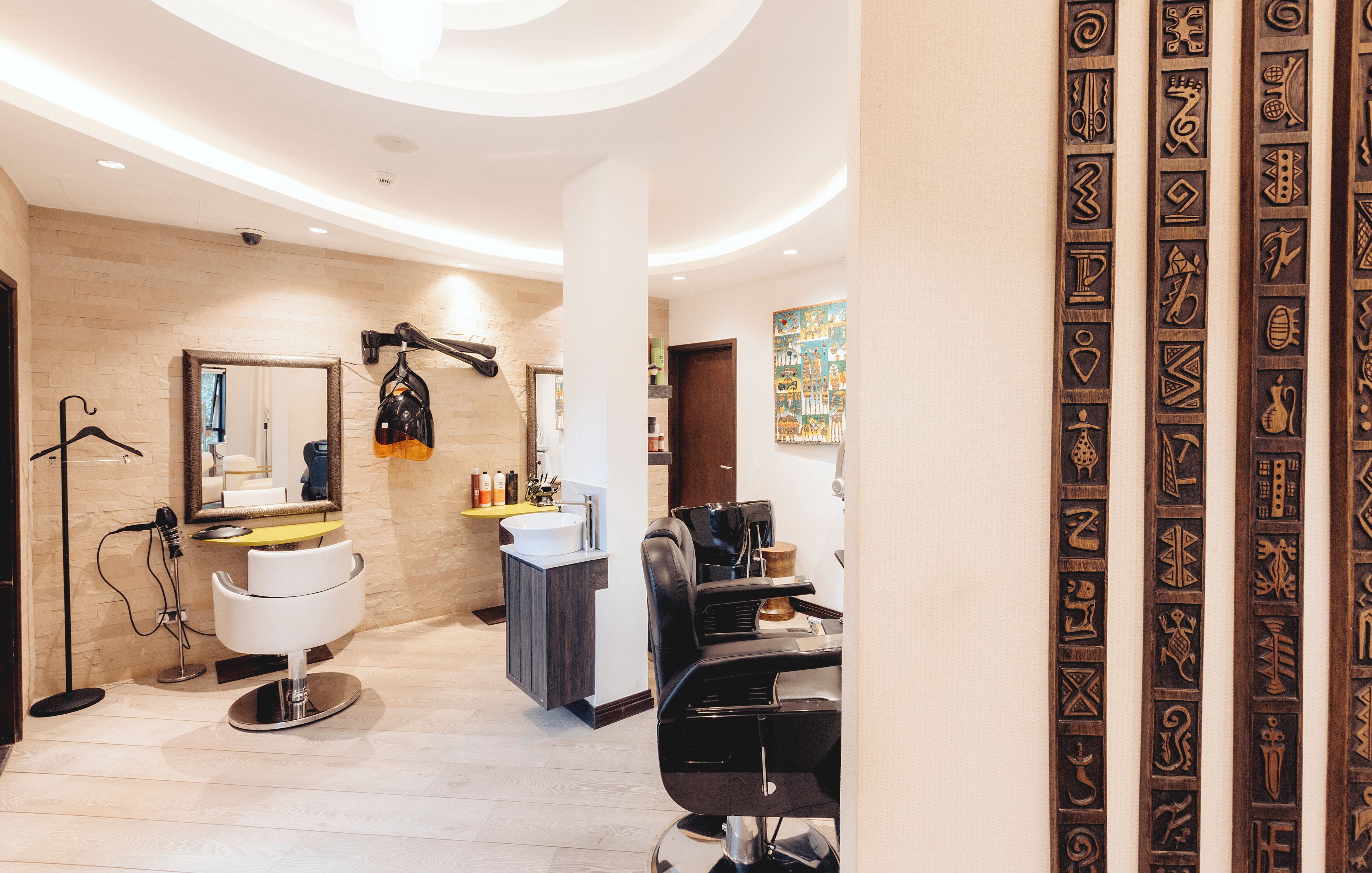 A modern hair salon with a large mirror, a hairdryer, and two salon chairs.