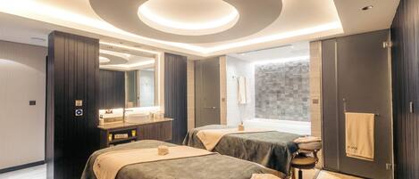 Een moderne hotelkamer met twee bedden, een grote spiegel, een badkamer met bad en een houten vloer.