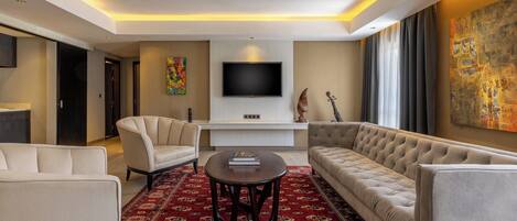 A modern living room with a sofa, armchairs, a coffee table, and a flat-screen TV mounted on the wall.