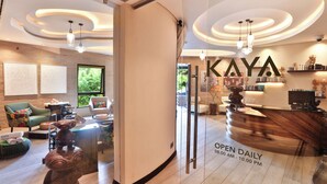 A modern hotel lobby with a reception desk, seating area, and a large window offering a view of greenery. - Tribe Hotel (Nairobi)