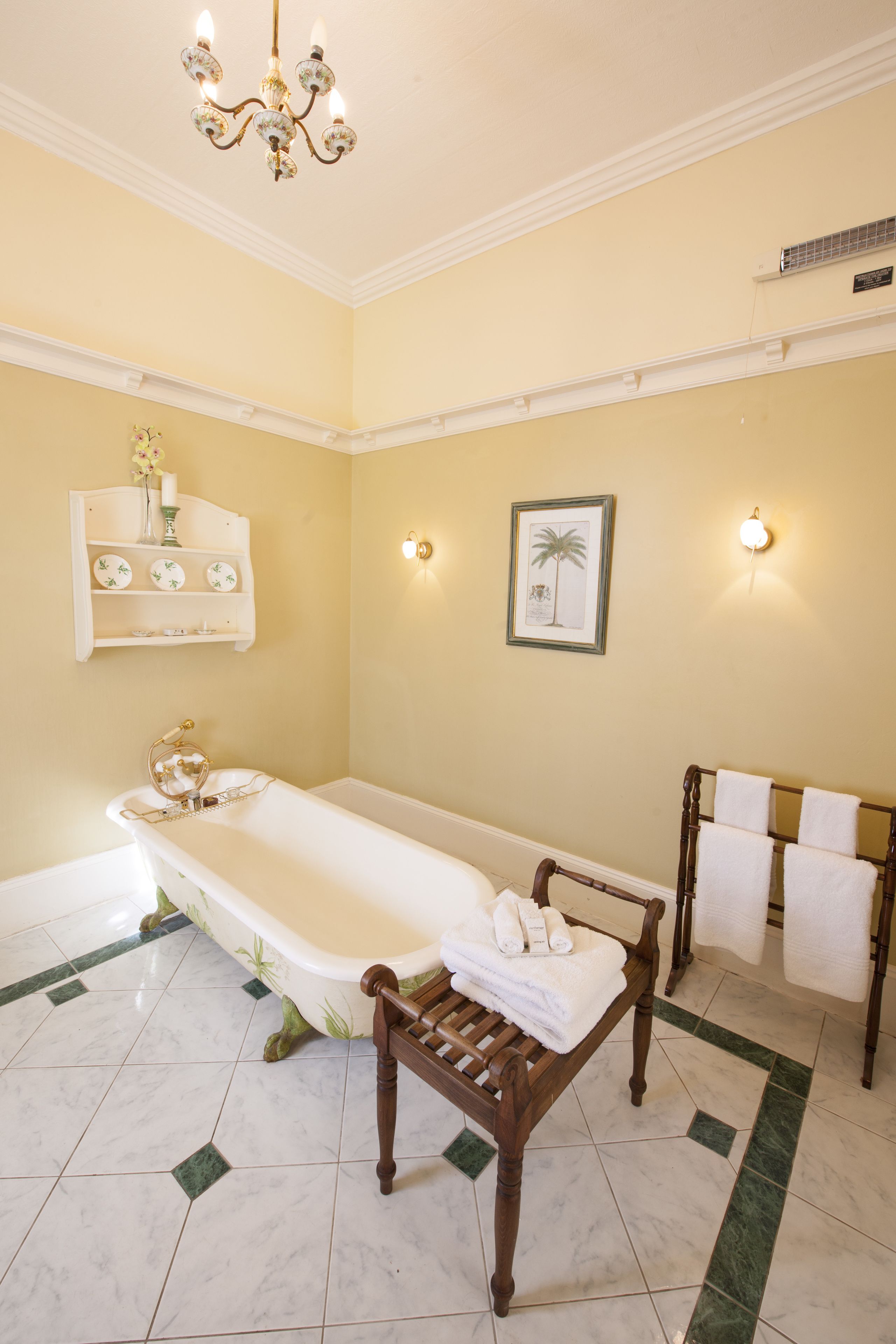 A bathroom with a freestanding bathtub, a wooden bench, a towel rack, and a wall-mounted shelf with decorative items.