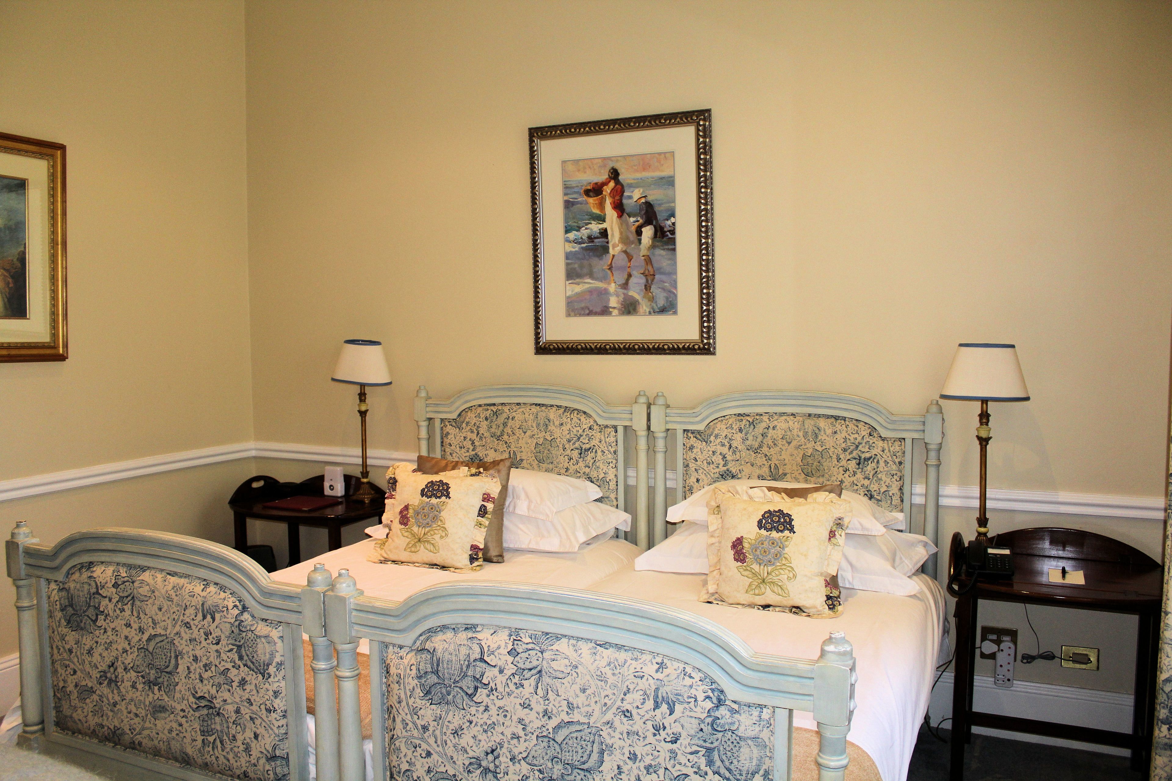 A bedroom with a bed, two bedside tables, a nightstand, a lamp, and a framed picture on the wall.